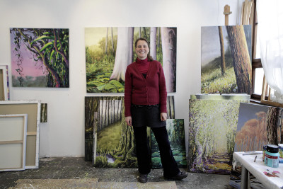 Anne Jannick in ihrem Atelier. Im Hintergrund sind einige der gezeigten Bilder zu sehen. (Foto: © der kunstbetrieb) 